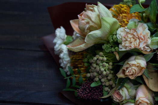 En bukett med olika blommor på ett mörkt bord.